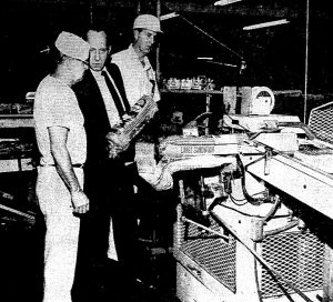 Bakery general manager George Cassem holds a loaf of bread at the bakery, 1971. Baker Fred Gillmore, left; production manager Robert Janzen, right. (Courtesy SJR files)